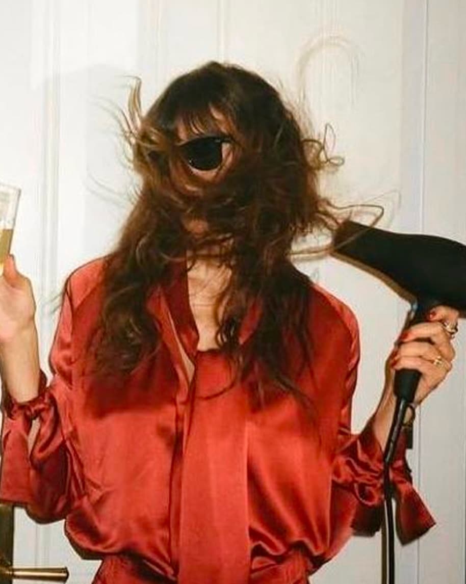 Client mid-blowout in a red silk shirt
